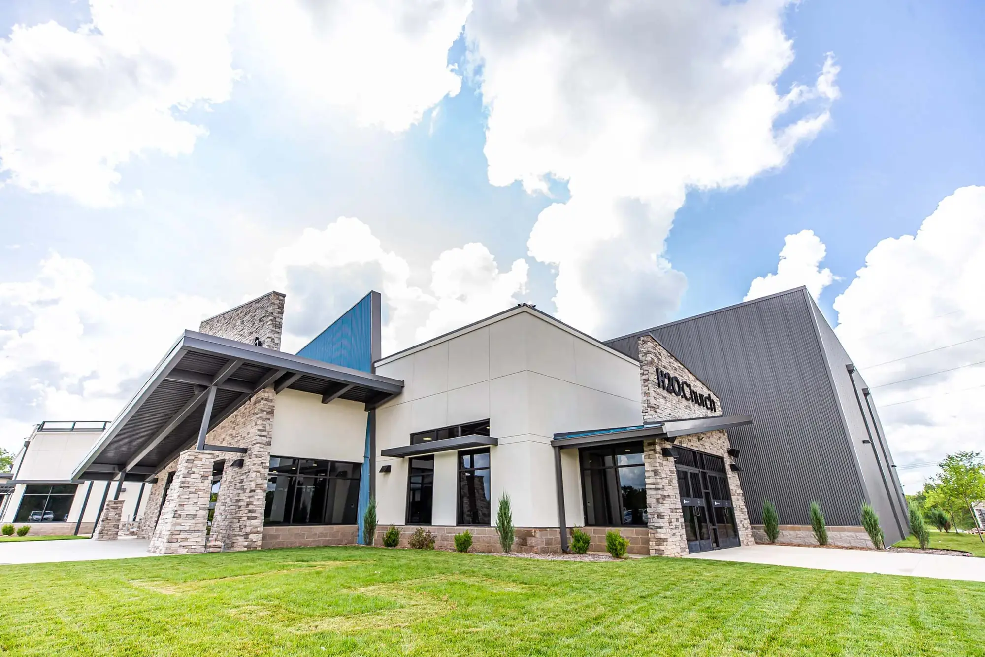 Exterior of H2O.Church with stone, metal panelling and a blue accent wall